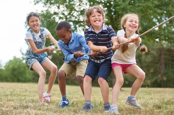 Spiel – vier Kinder ziehen gemeinsam an einem Seil in eine Richtung